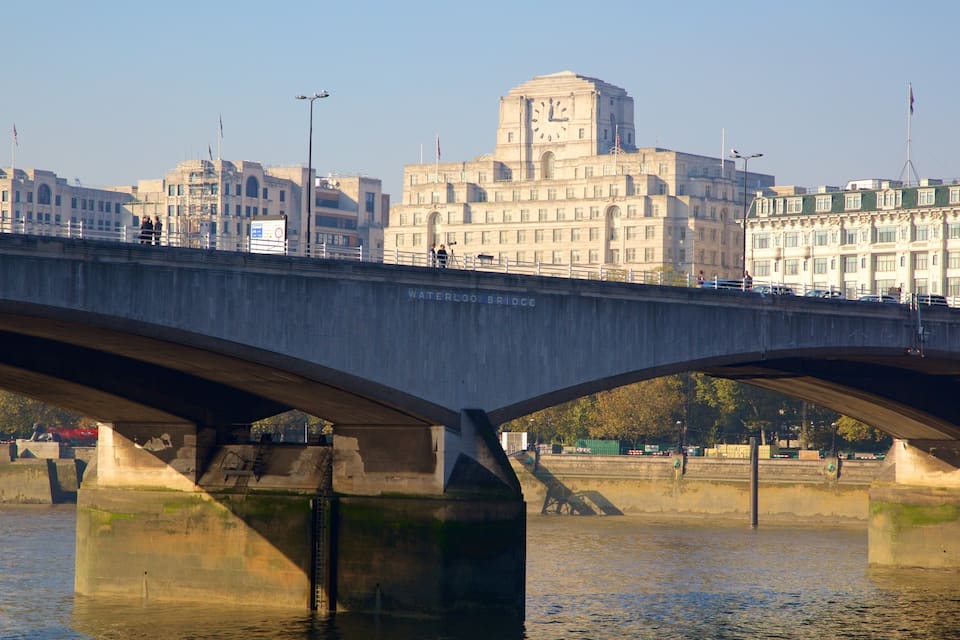 Een brug over een rivier, met een stadsgezicht op de achtergrond.