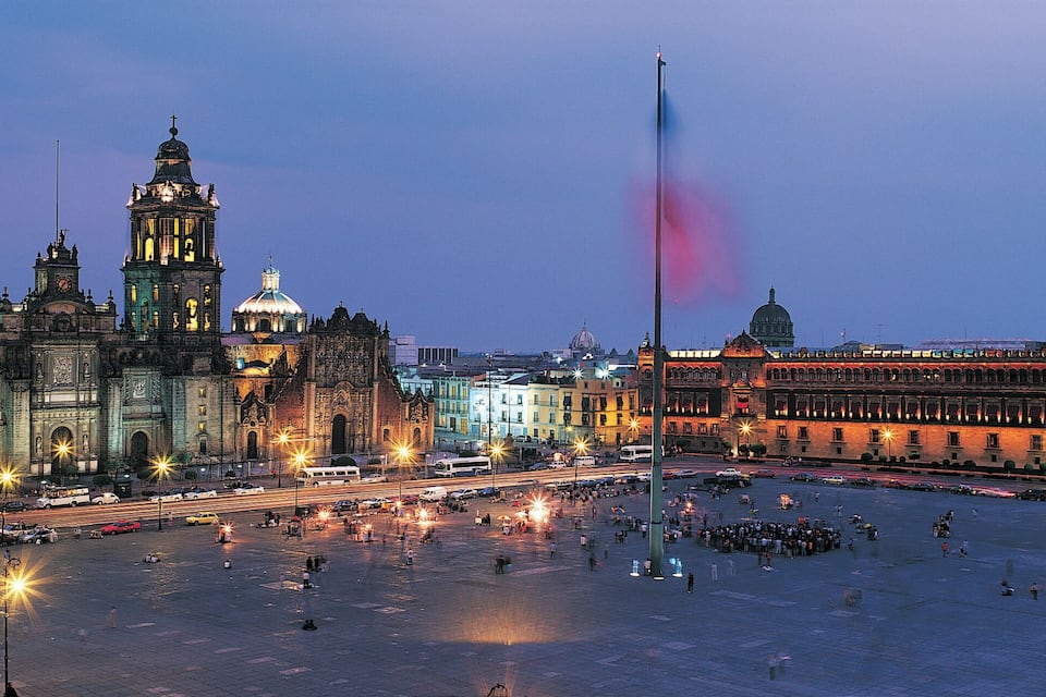 Una plaza urbana con edificios históricos y una bandera.
