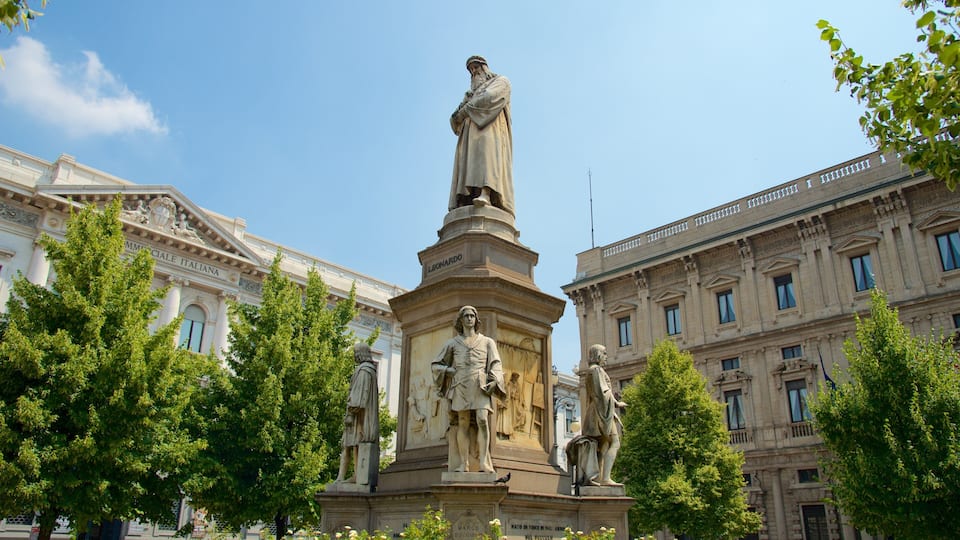 Uma estátua de uma figura histórica em uma praça com árvores e arquitetura clássica ao fundo.