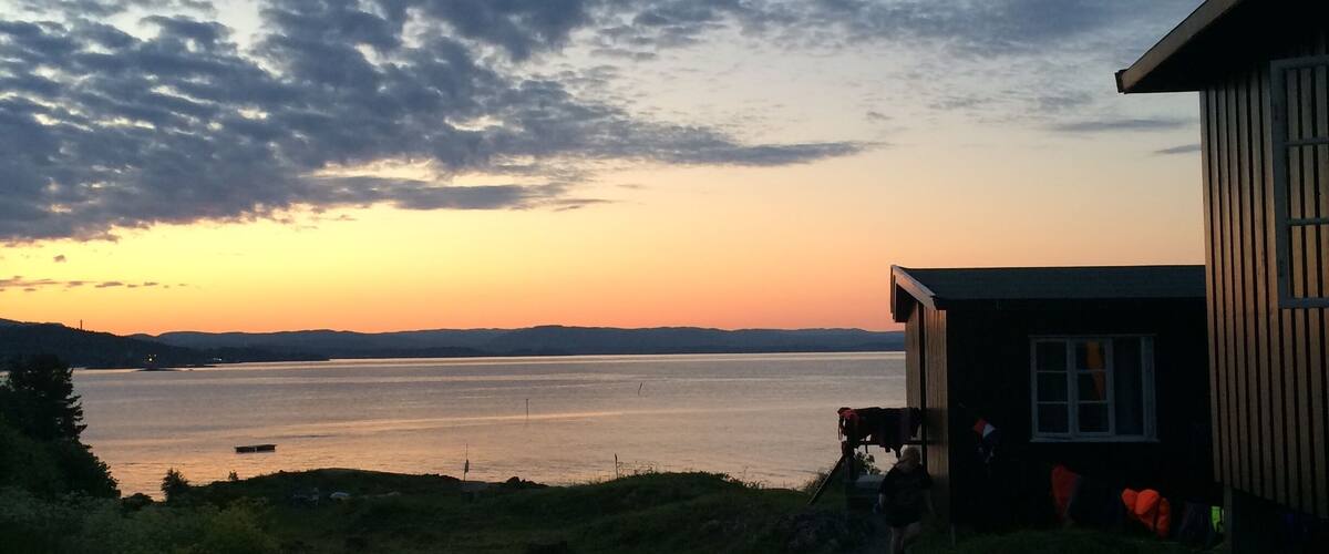 A sunset over a calm lake with a wooden cabin on the right.