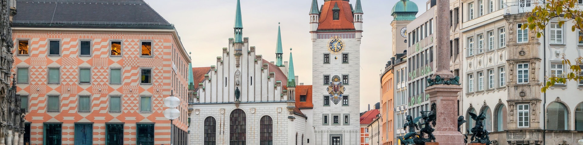 A historic square with a church, a clock tower, and a statue.
