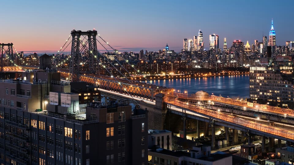 Un horizonte urbano al anochecer con puentes e edificios iluminados.