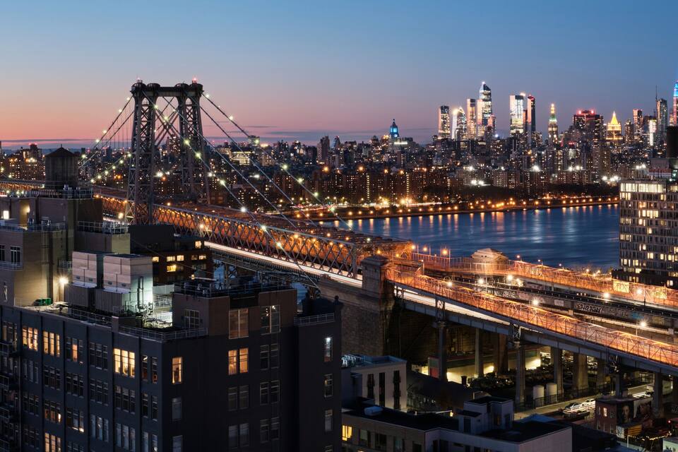 A city skyline at dusk with illuminated bridges and buildings.