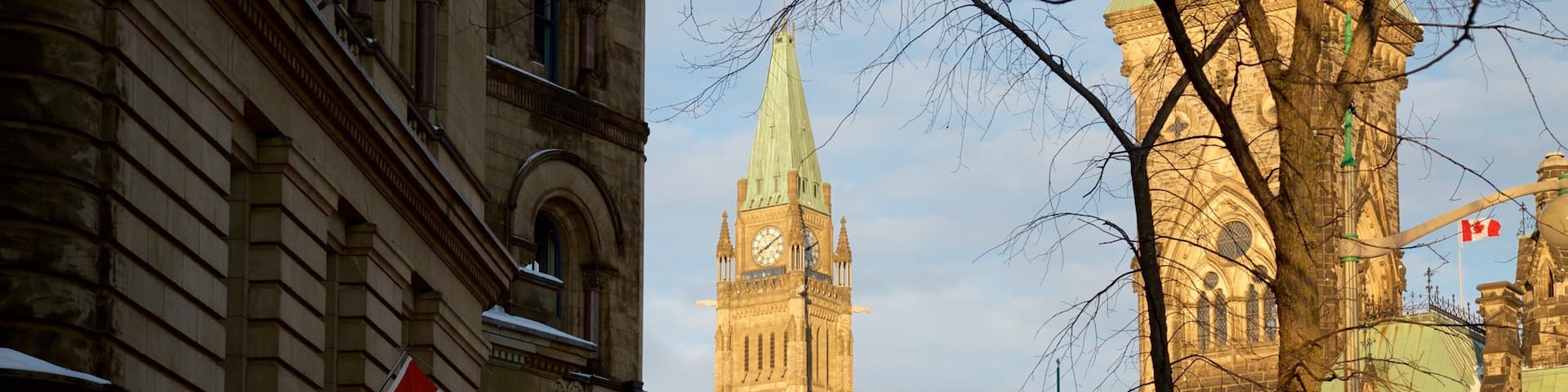 A snow-covered street with historic buildings, a clock tower, and a Canadian flag.