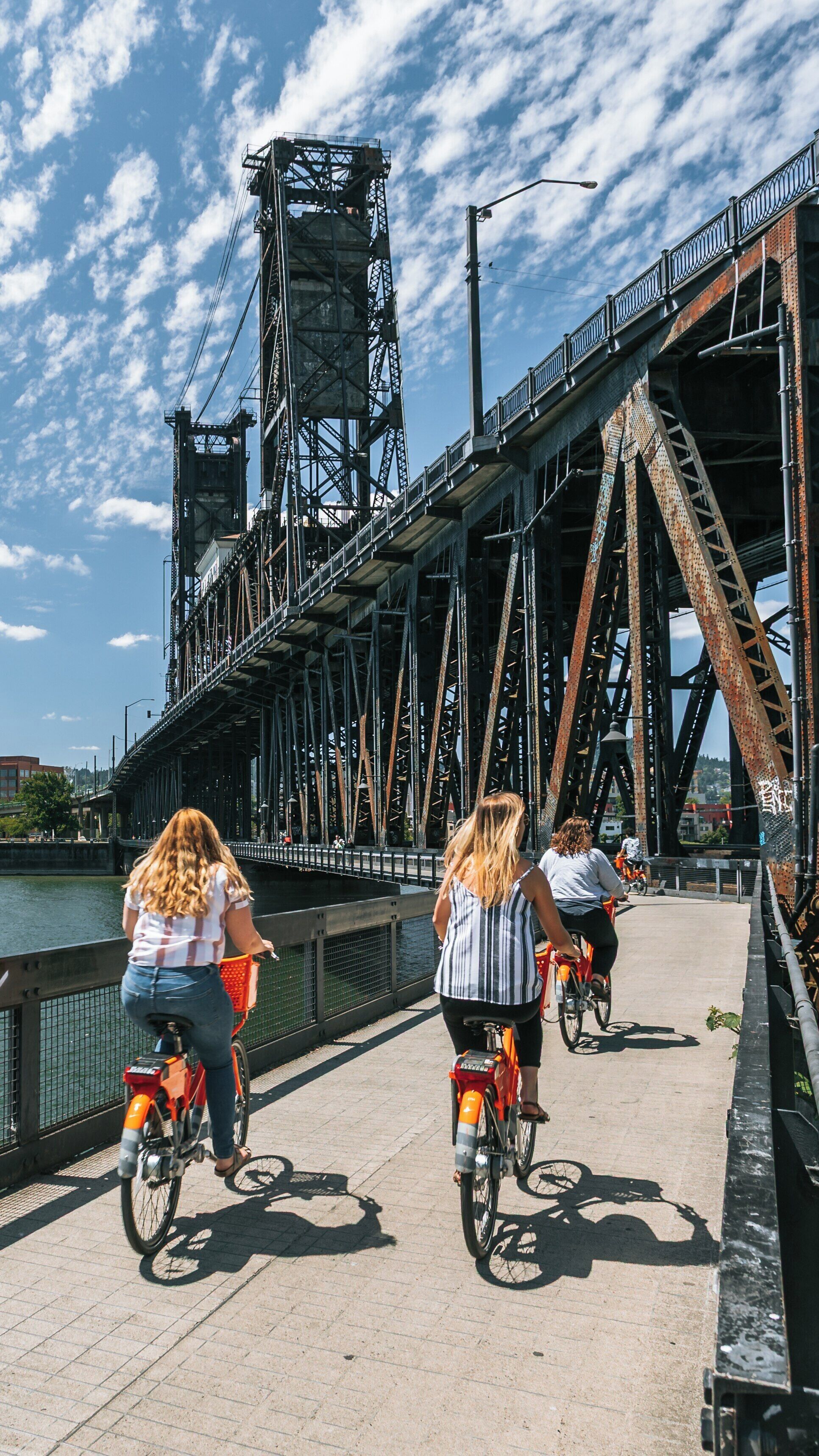 Bicyclists enjoying a sunny day at Steel Bridge in Lloyd District, Portland, Oregon, while traversing along the waterfront pathway