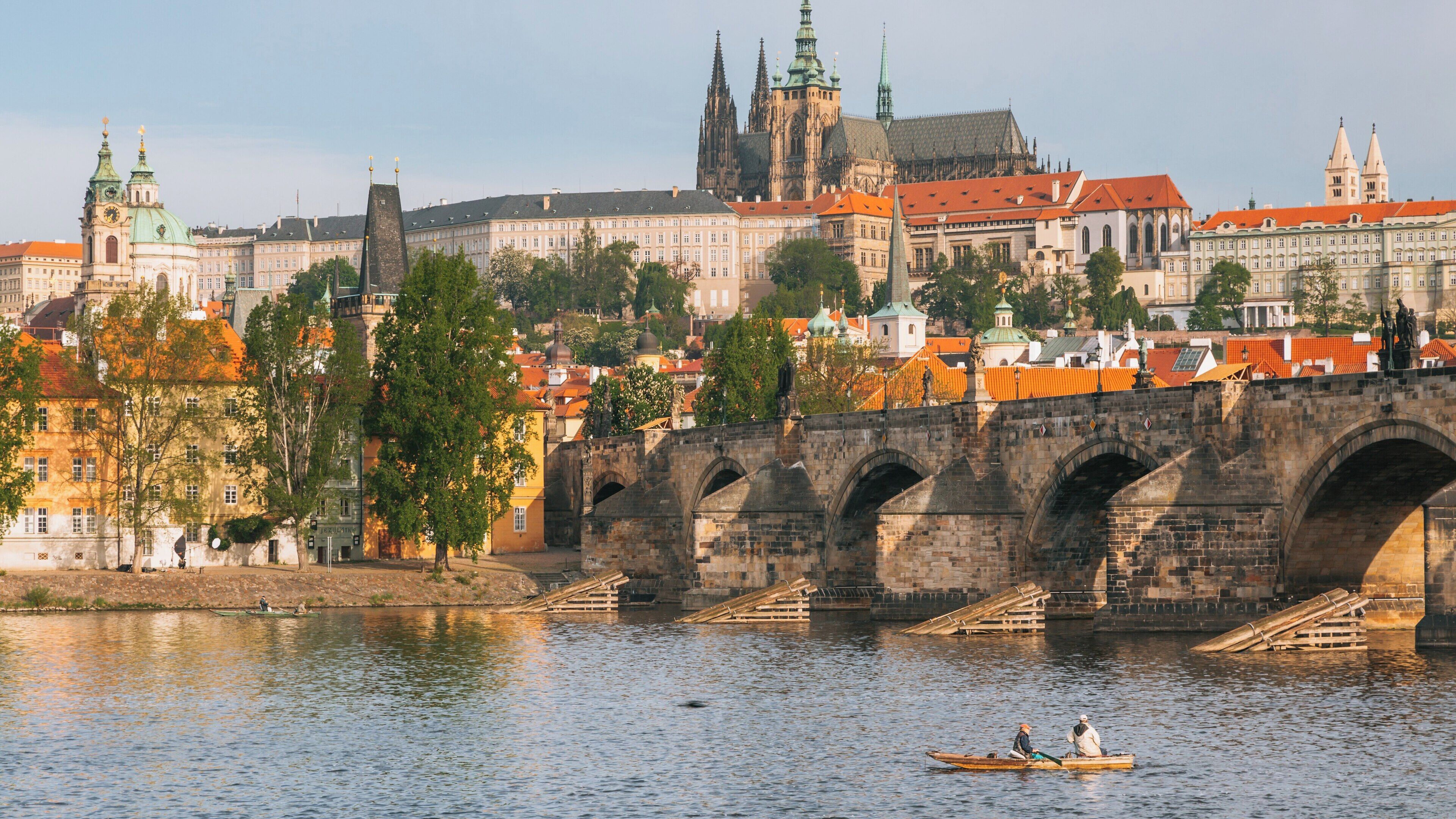 Beautiful view of Charles Bridge and Prague Castle over Vltava River with kayakers enjoying a serene afternoon in Czechia