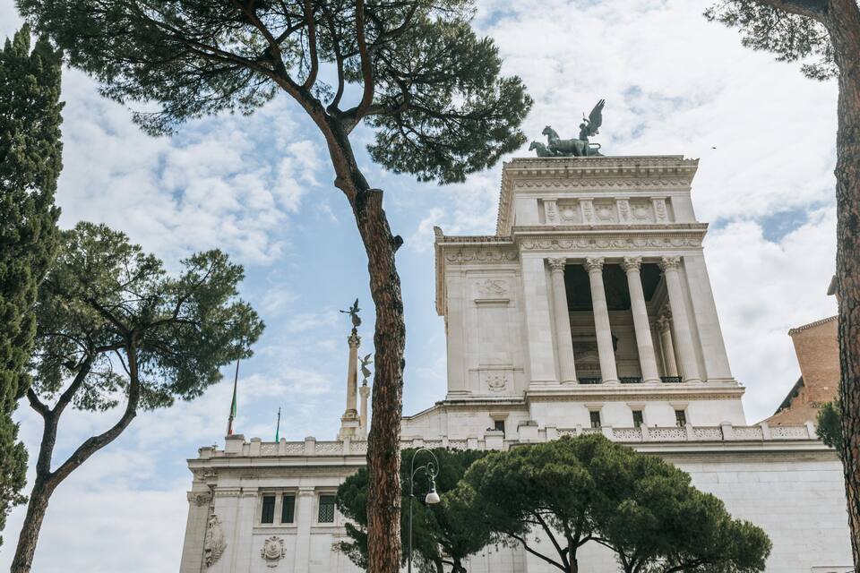 A neoclassical building with columns and a statue on top.