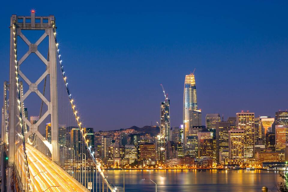 A city skyline with a prominent bridge and illuminated buildings.