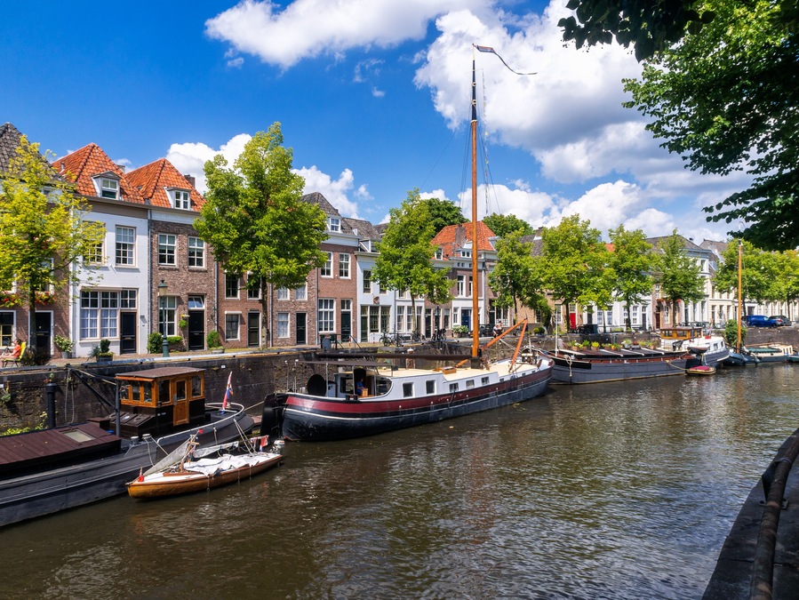 Ein Kanal mit Booten, historischen Gebäuden und Bäumen.
