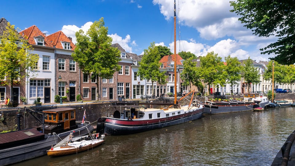 A canal with boats, historic buildings, and trees.