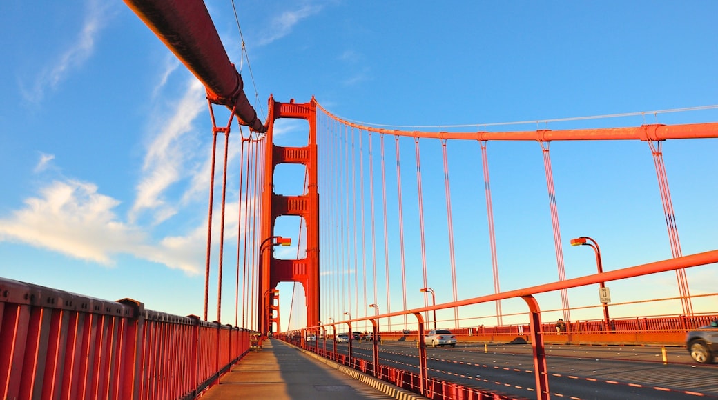 Golden Gate Bridge stretches over the bay in bright blue skies with vibrant architecture and bustling traffic in California