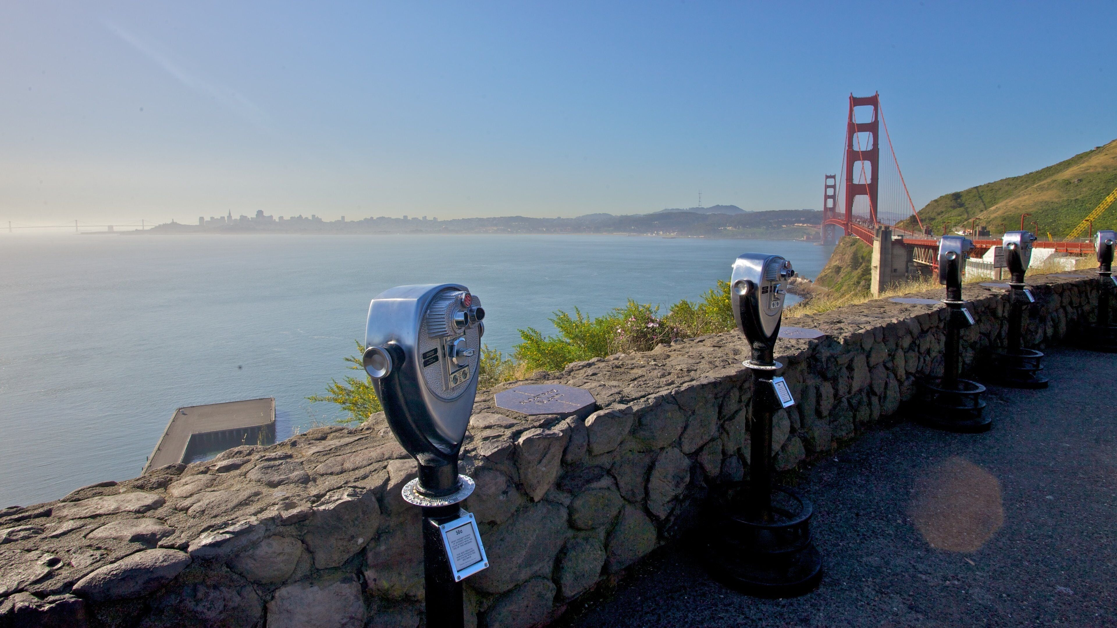 Golden Gate Bridge viewed from a lookout point with observation telescopes on a clear morning