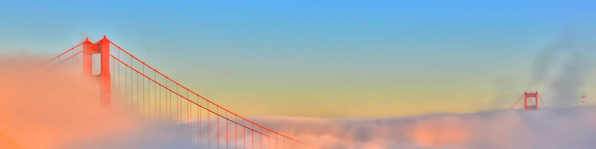 Golden Gate Bridge rises above fog at sunrise in San Francisco Bay area California