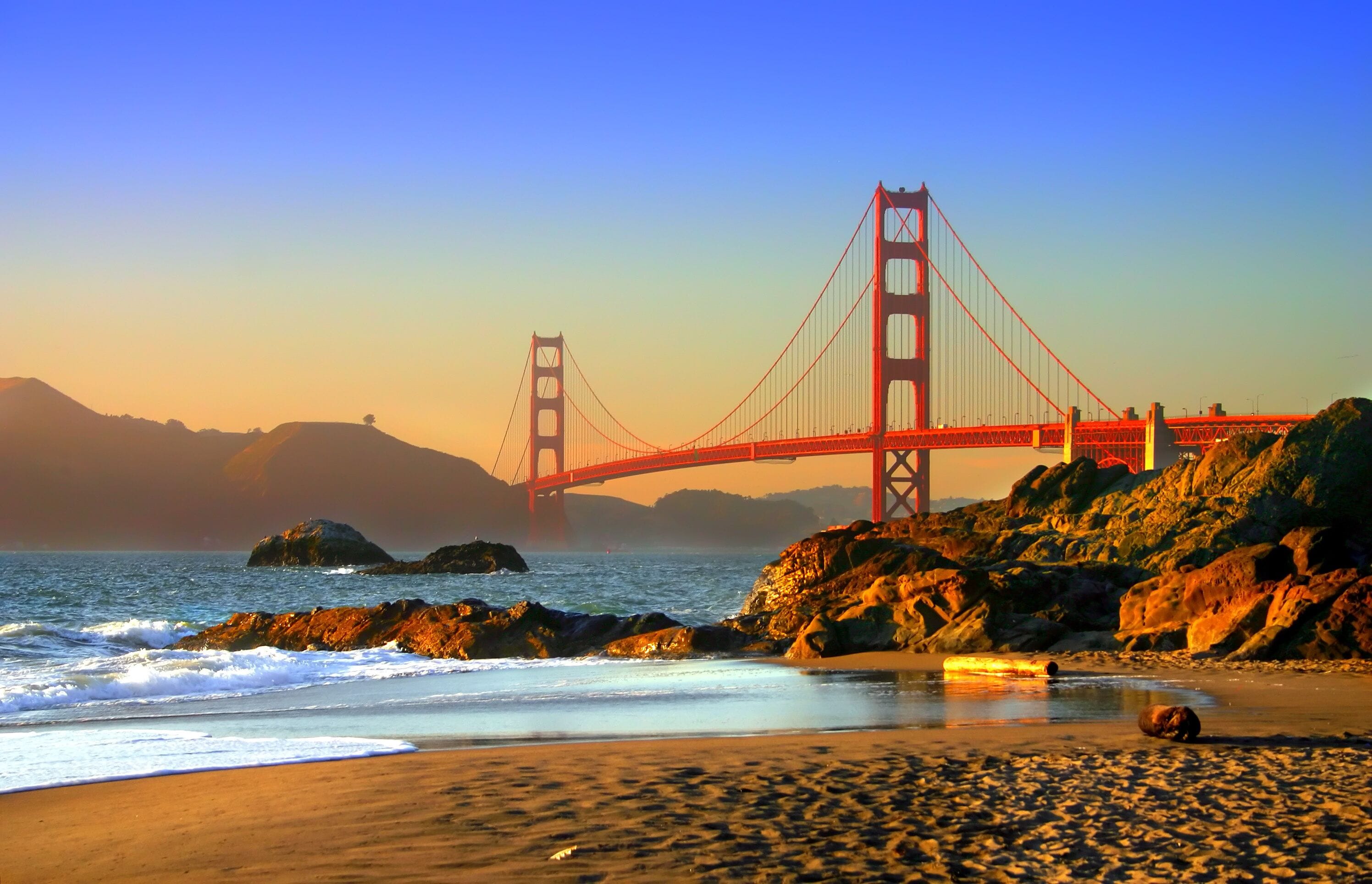 The Golden Gate Bridge, ocean waves, and rocky coastline.