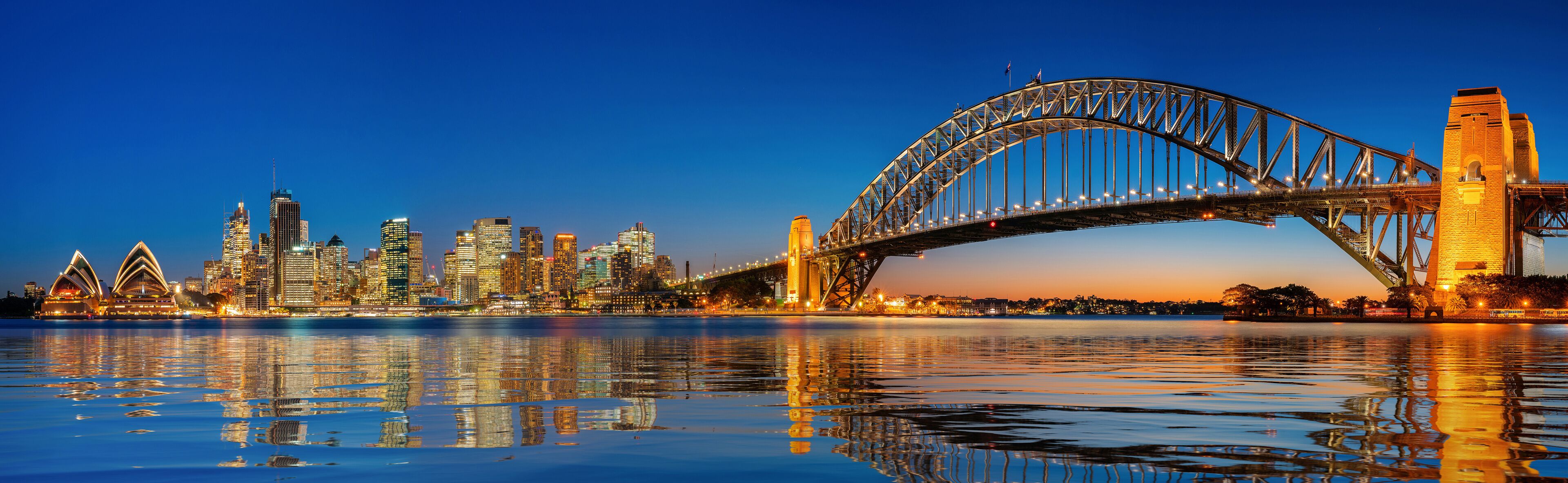 Un horizonte urbano con un puente destacado que se refleja en el agua.