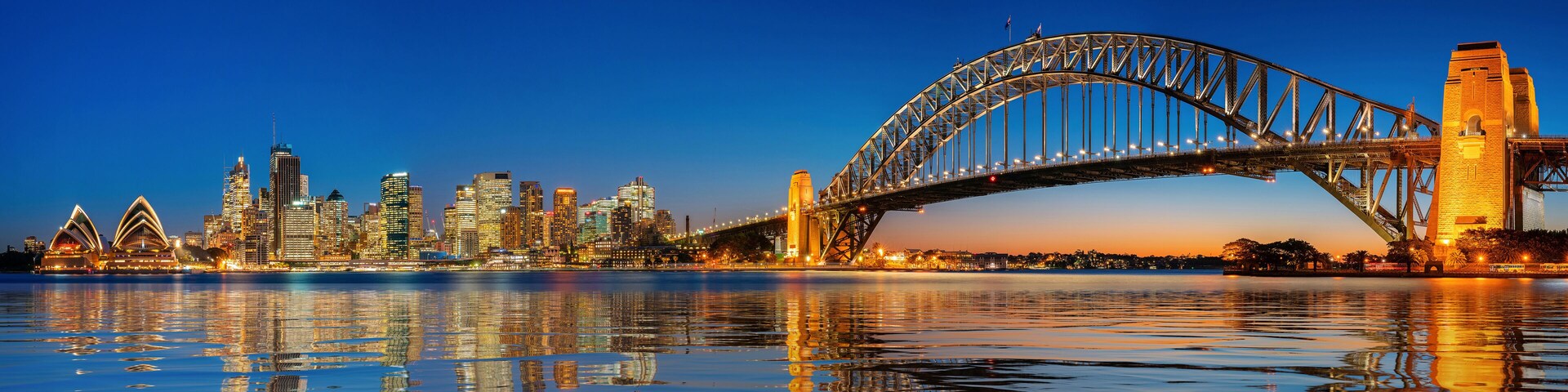 Un horizonte urbano con un puente destacado que se refleja en el agua.