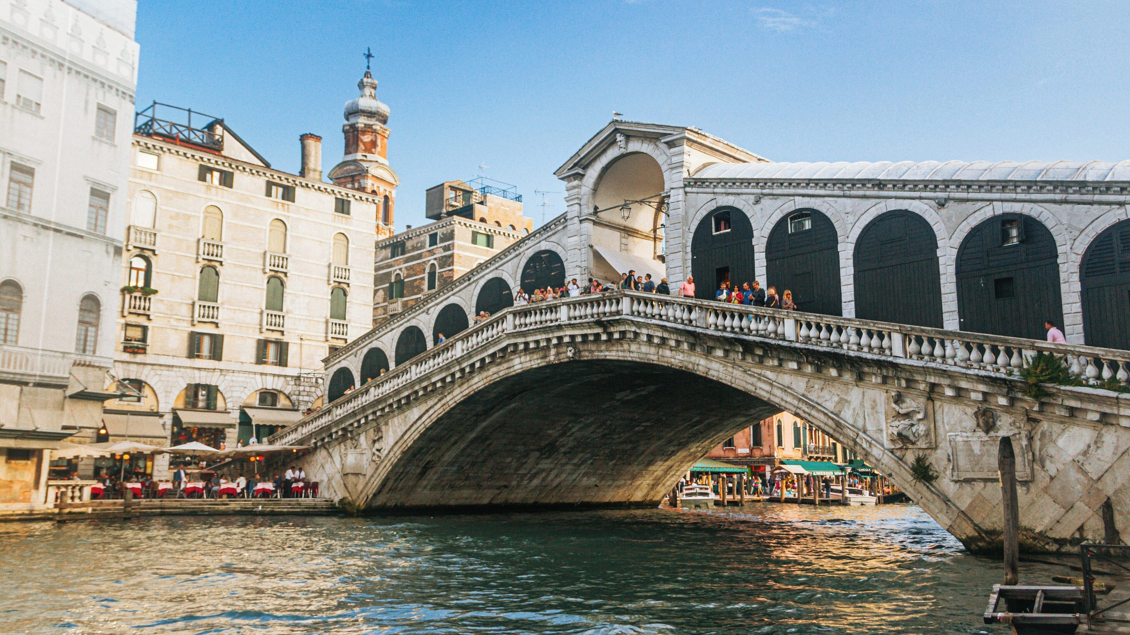 Rialto Bridge in Venice City Center showcases beautiful architecture and bustling activity along the Grand Canal during a sunny day