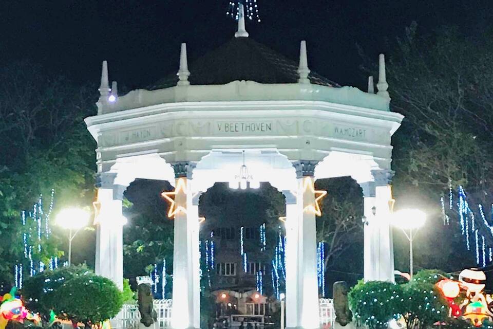 A white gazebo with star-shaped lights and a large star above it.