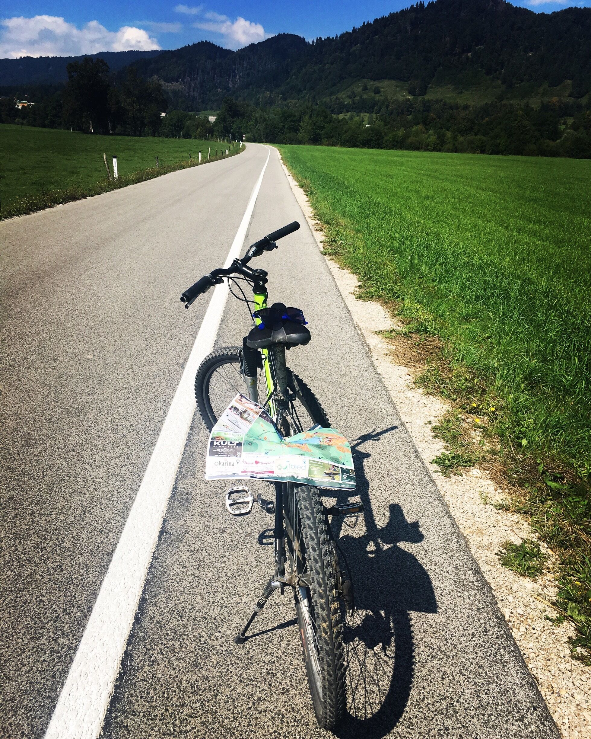 A bicycle parked on a road with a map attached to the frame.