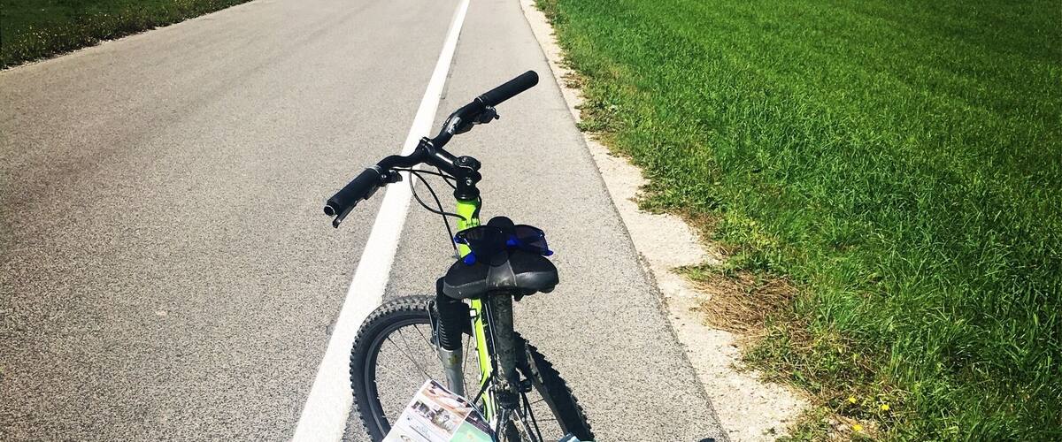 A bicycle parked on a road with a map attached to the frame.