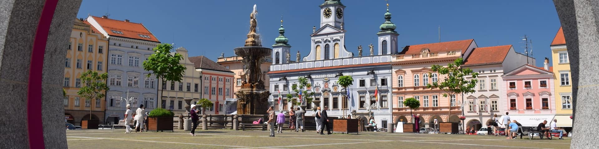A historic square with a prominent church, a fountain, and colorful buildings.