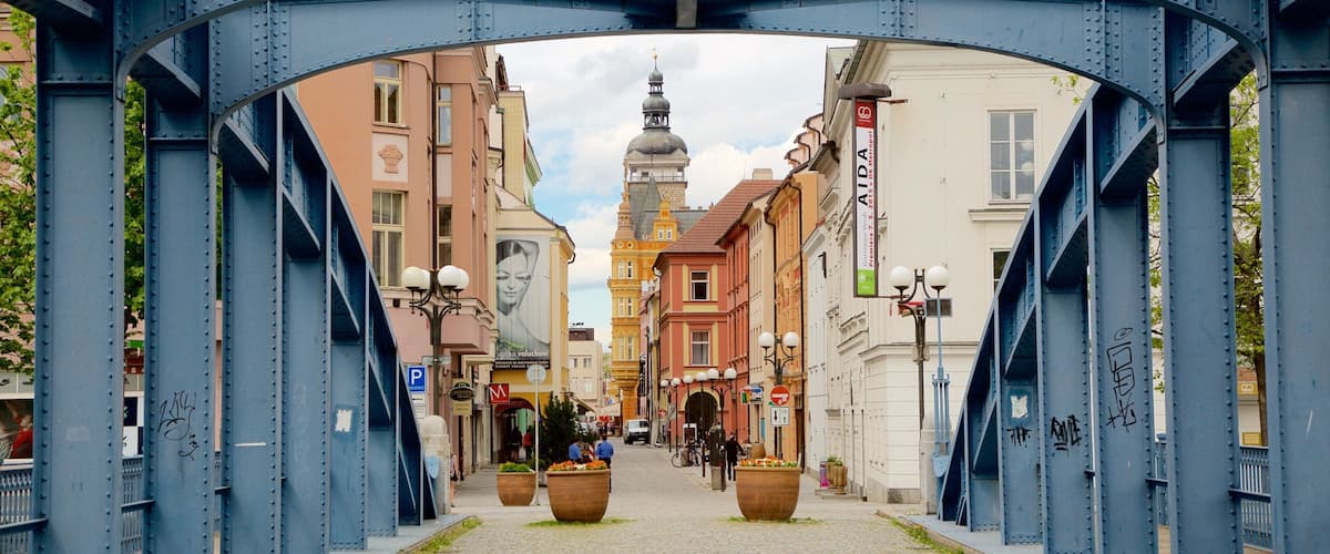 A cobblestone street under a blue bridge with historic buildings and a church tower in the background.