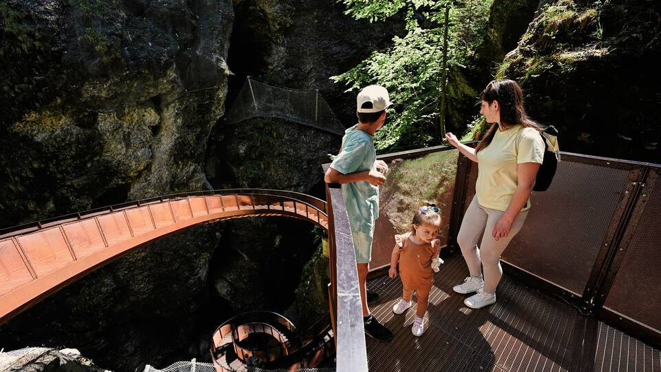 A bridge over a rocky gorge with a spiral staircase descending into the gorge.