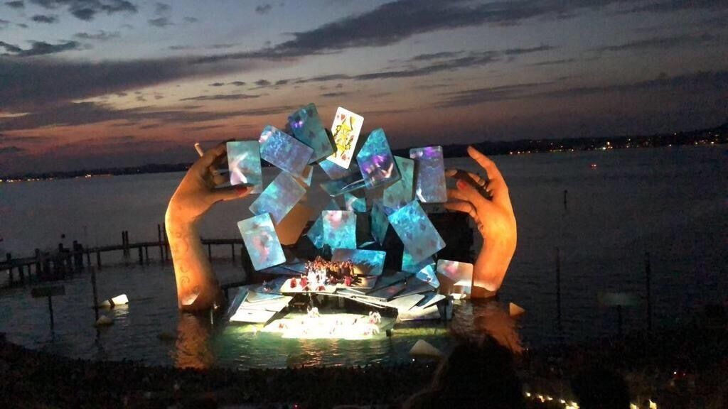 A nighttime outdoor event with illuminated crystal sculptures and a boat on a body of water.