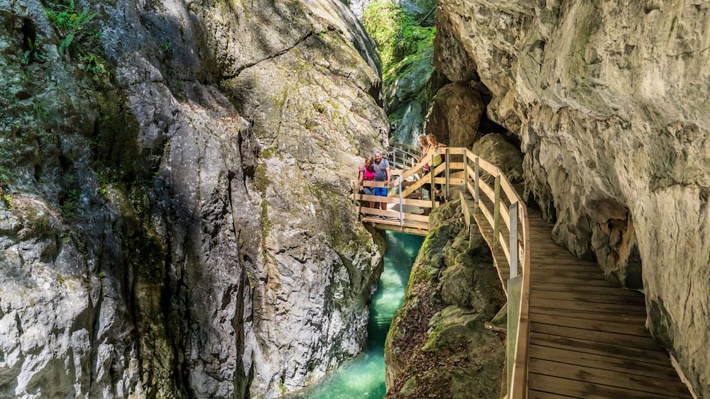Eine HolzbrĂŒcke ĂŒber einer schmalen Schlucht mit klarem Wasser.