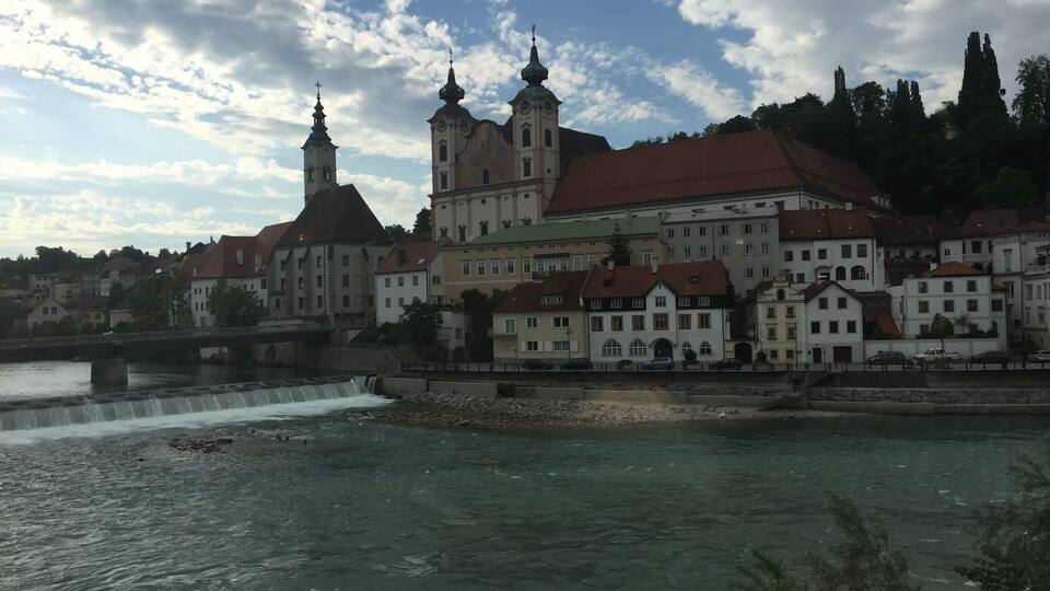 A historic building with two towers and a river in the foreground.