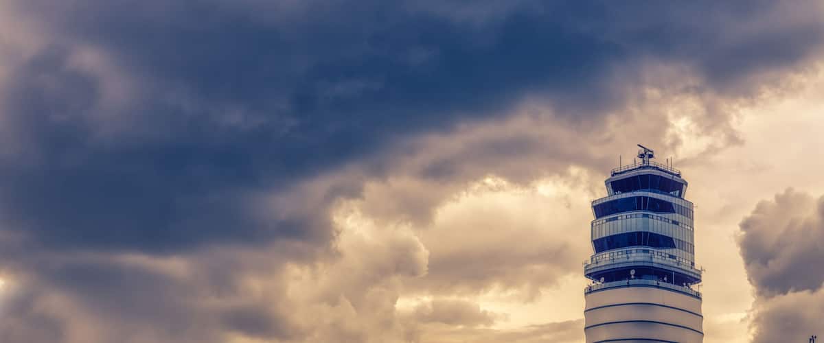 A tall, cylindrical tower with a spiral staircase against a backdrop of dramatic, stormy clouds.