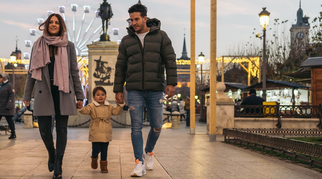 Father, mother and daughter walking hand in hand through the city center decorated for Christmas. Walk through the historic center of Alcala de Henares, Madrid.