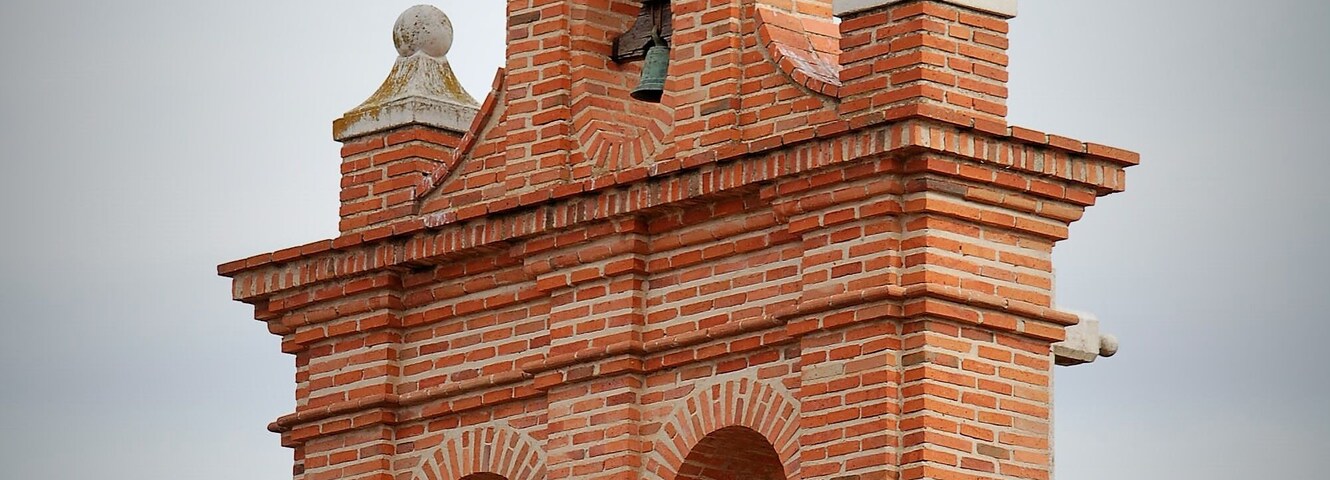 Una torre de ladrillo con un pájaro posado en la cima.