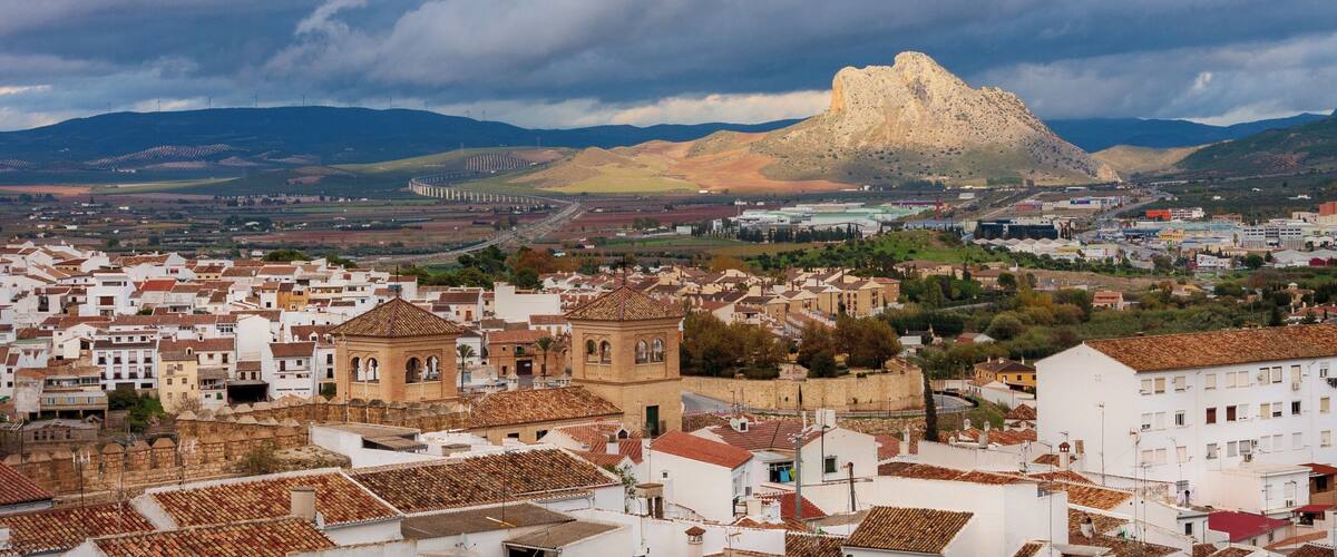 A town with white buildings and a prominent hill in the background.