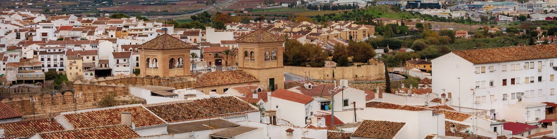 A town with white buildings and a prominent hill in the background.