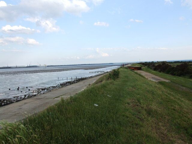 A coastal landscape with a grassy path, a sandy beach, and a calm sea.