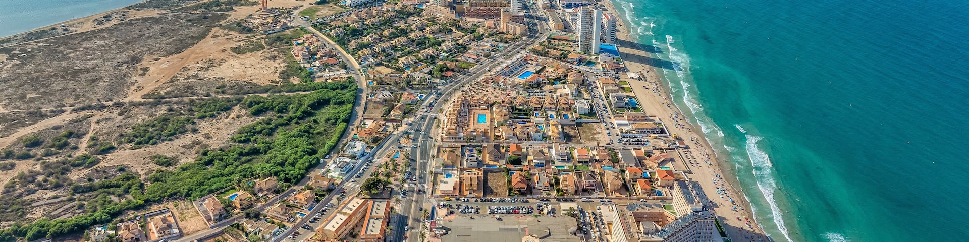 Aerial view of La Manga seaside spit of Mar Menor in the Region of Murcia, Spain, long strip full of hotels, vacation homes popular for local tourists