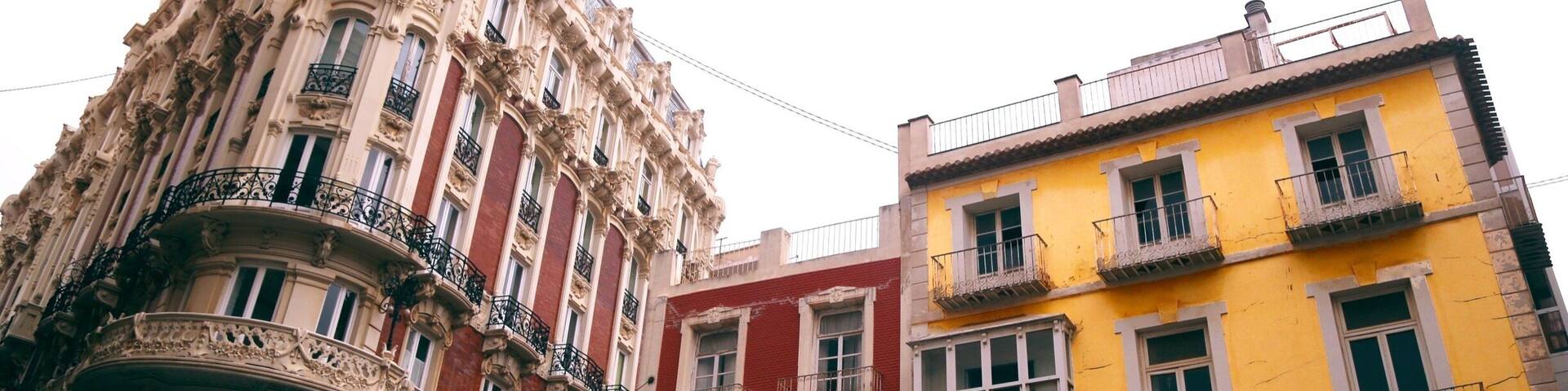 A historic building with ornate architecture and a yellow building with balconies.