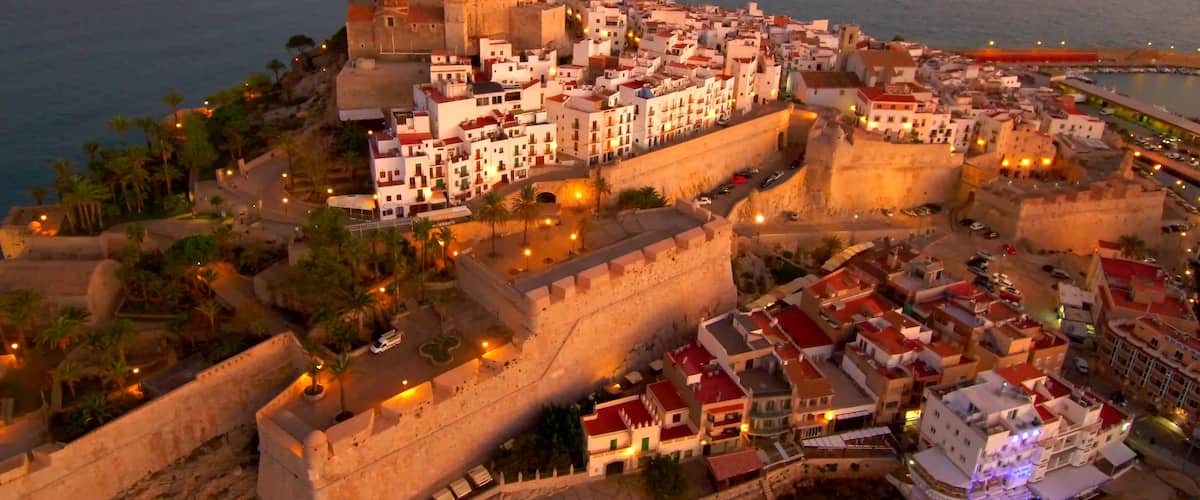 A coastal city with a prominent castle, narrow streets, and a mix of historic and modern buildings.