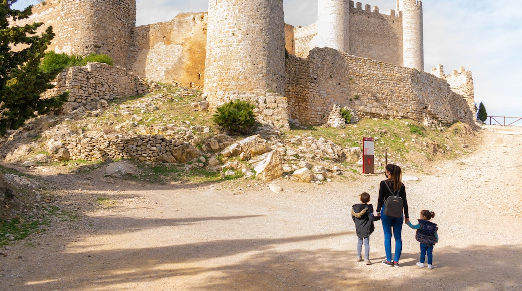familia de mujer y dos niños cogidos de la mano, paseando delante de las ruinas del castillo de Alcalá de xivert , provincia de Castellón de la plana , España