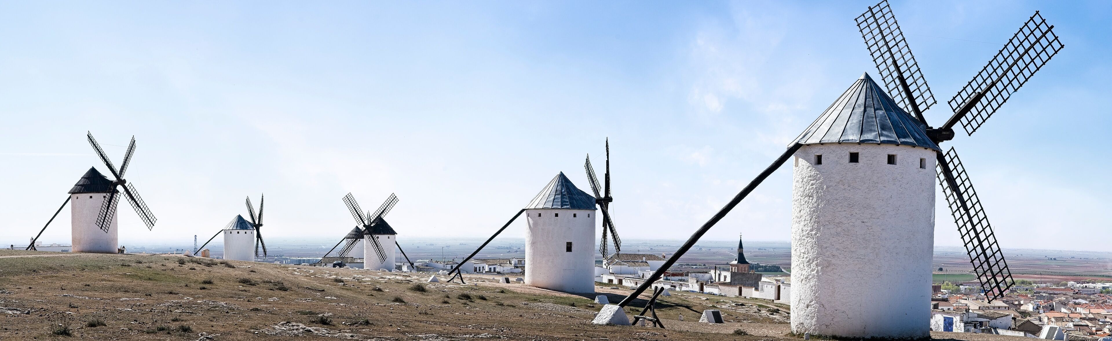 A landscape with multiple windmills and a distant view of a town.