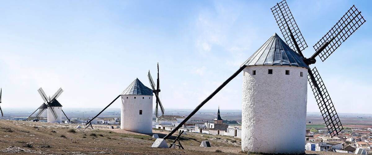 A landscape with multiple windmills and a distant view of a town.