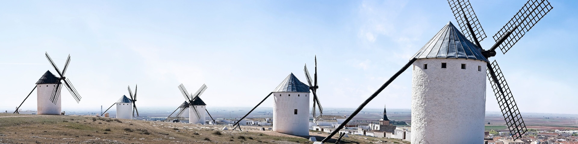 A landscape with multiple windmills and a distant view of a town.