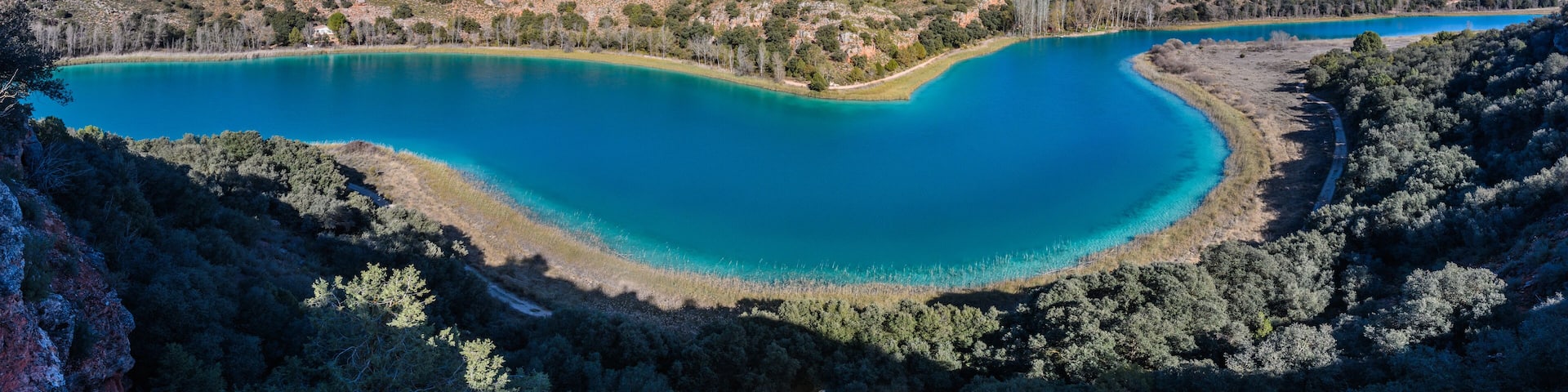 A turquoise lake surrounded by forested hills.