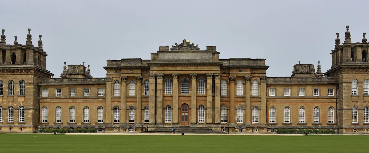 A large, historic building with symmetrical architecture, featuring tall columns, arched windows, and decorative elements on the roof.