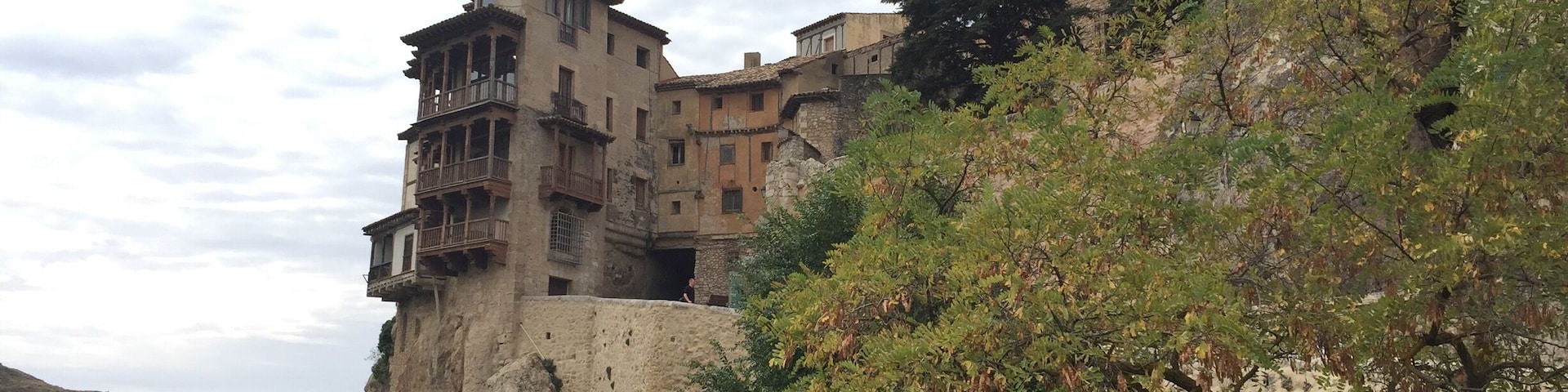 Un edificio de piedra histórico asentado en un acantilado con abundante vegetación al frente.