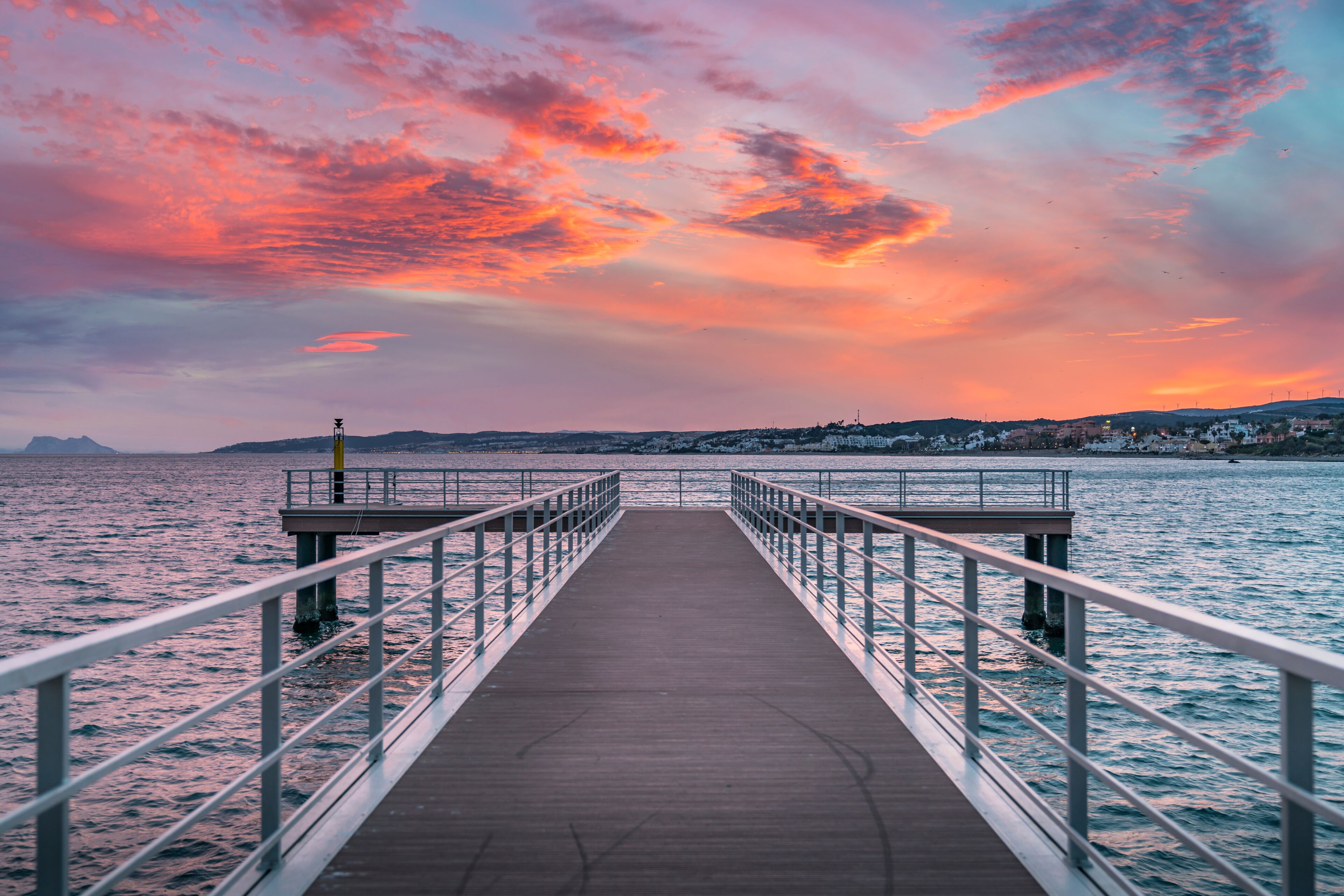 A pier extending into a body of water with a sunset sky.