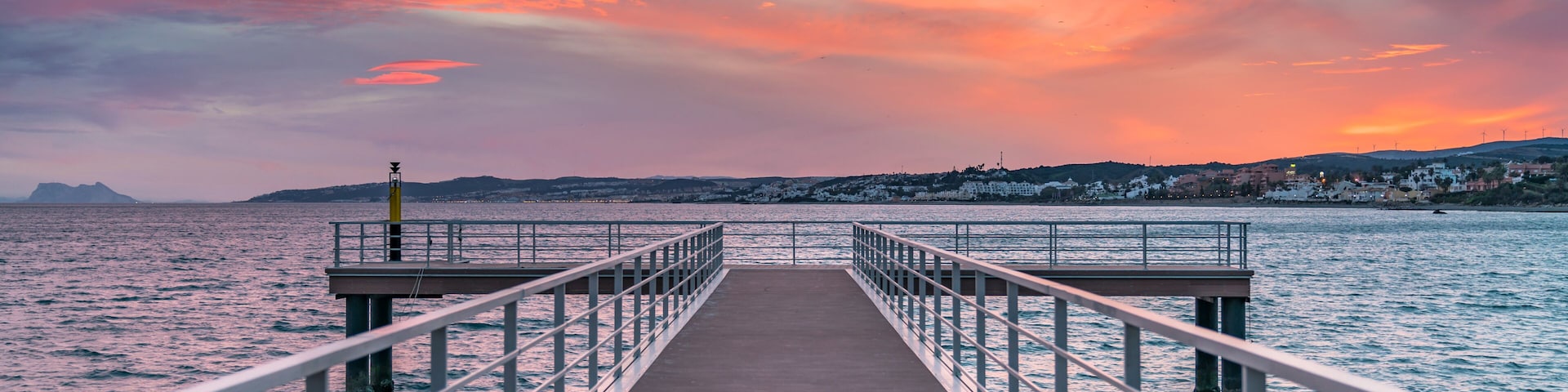 A pier extending into a body of water with a sunset sky.