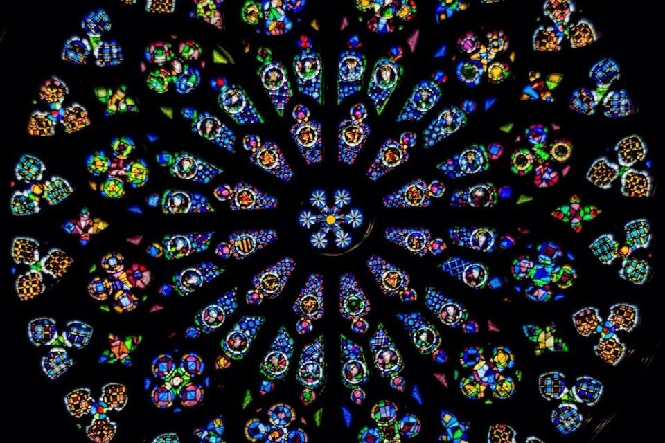 A circular stained glass window with intricate patterns and vibrant colors.