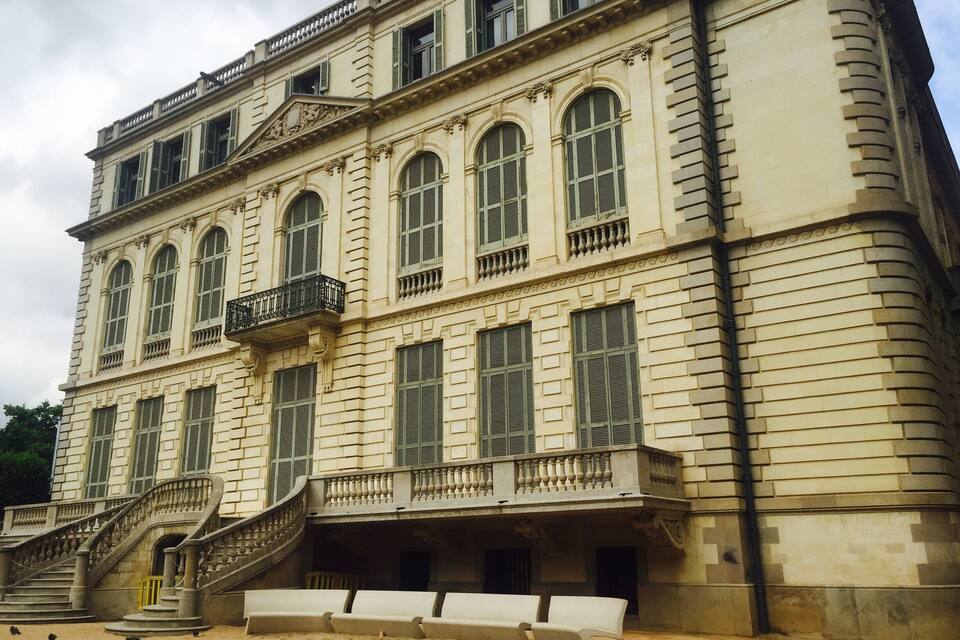 A historic building with a grand staircase, multiple arched windows, and a balcony.